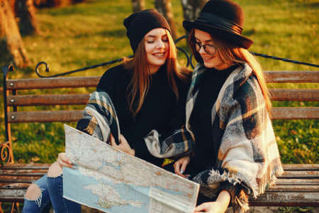 two young girls walk around the city in the autumn city and parkの写真素材