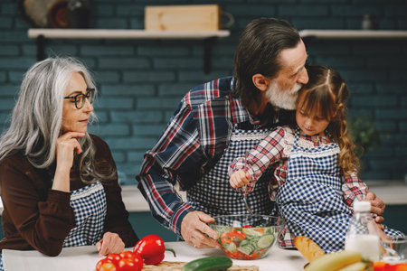 Cute girl and her grandparents cooking in kitchenの写真素材