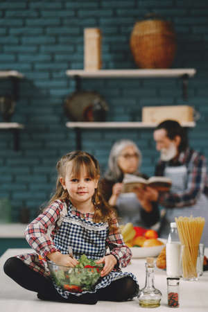 Little girl eating in the kitchen with granparentsの写真素材