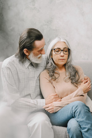 Senior couple in casual clothes sitting on couch in living room
