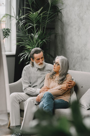 Senior couple in casual clothes sitting on couch in living room