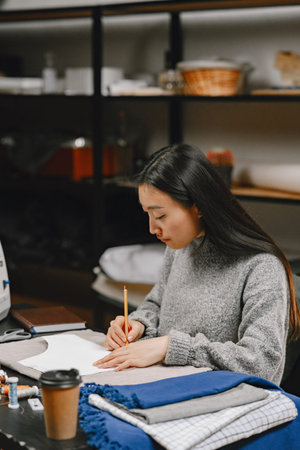 Professional young female tailor working in workshop