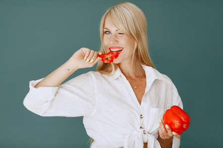 Beautiful and sporty girl in a kitchen with a vegetablesの写真素材