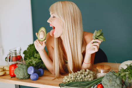 Beautiful and sporty girl in a kitchen with a vegetablesの写真素材