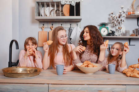 Cute sisters standing in a kitchen and eats bunsの写真素材