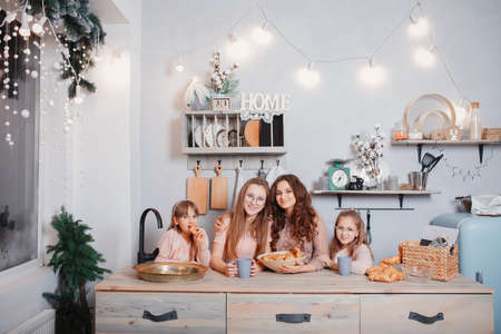 Cute sisters standing in a kitchen and eats bunsの写真素材