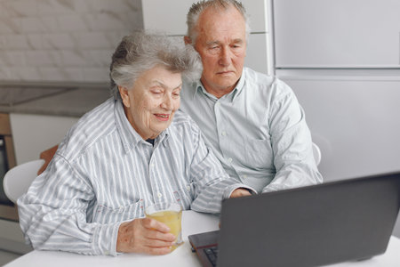 Elegant old couple sitting at home and using a laptop