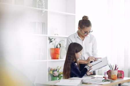 Tutor with litthe girl studying at homeの写真素材