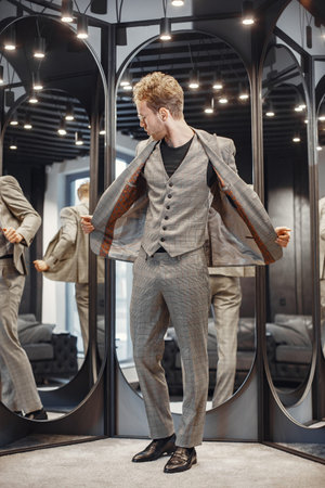Handsome man with beard choosing jacket in a shop