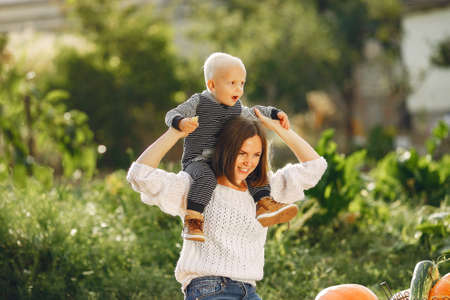Mother and son sitting on a garden near many pumpkinsの写真素材