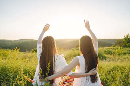 Portrait of two sisters in white dresses with long hair in a fieldの写真素材