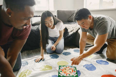 Three friends playing twister in the living roomの写真素材