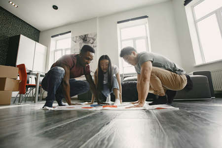 Three friends playing twister in the living roomの写真素材