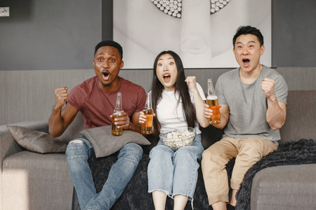 Three friends watching a football and drink beer
