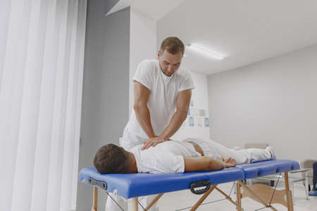 Male physiotherapist massaging mans backの写真素材