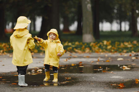 Funny kids in rain boots playing with a puddleの写真素材