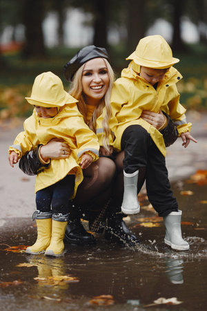 Funny kids in rain boots playing in a rain park