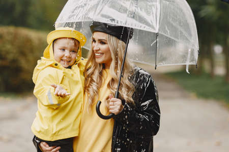 Funny kids in rain boots playing in a rain parkの写真素材