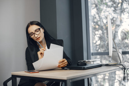 Woman sitting at a desk in the office and reading documents.