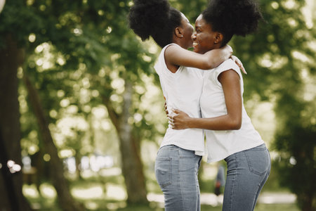 Two afro-american sisters hugging in a park