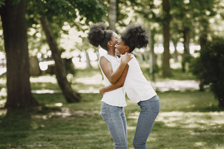 Two young afro-american sisters hugging in a parkの写真素材