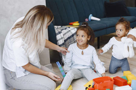 Cute little girls and their mother playing with toys on the floor near the couchの写真素材