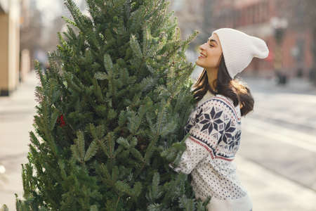 Cute brunette in a white sweater with Christmas treeの写真素材