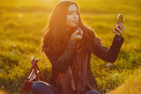 brunette girl doing her make up in the parkの写真素材
