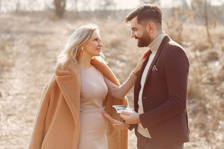 Pregnant woman standing in a park with her husbandの写真素材