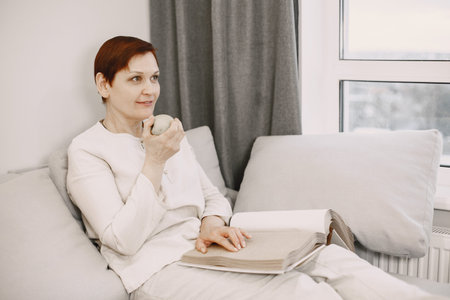 Mature woman read braille book on couch
