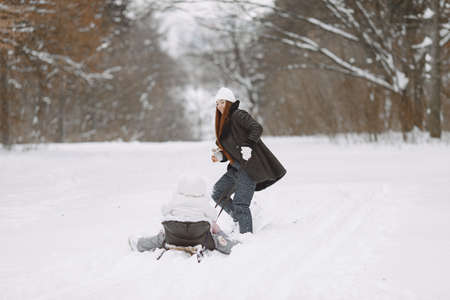Mother and child in winter clothes play in winter parkの写真素材