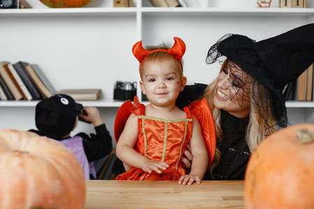 Family in costumes getting ready for halloween at homeの写真素材