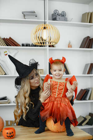 Family in costumes getting ready for halloween at homeの写真素材