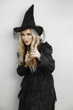 Woman wearing black costume. Lady with halloween makeup. Girl on a white background.