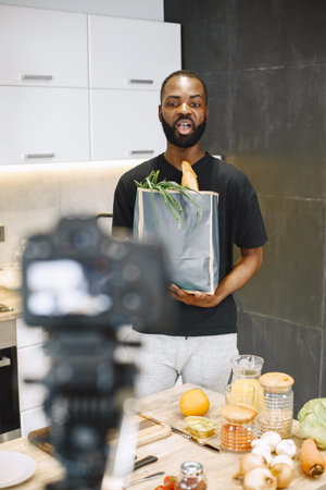 African male blogger recording vlog on digital camera