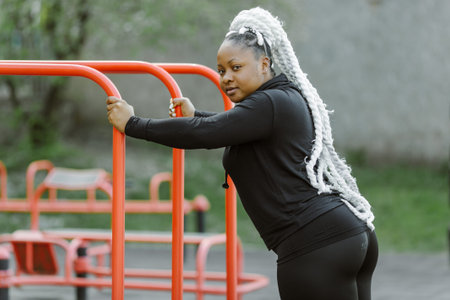 Afro-american plus size woman doing workout exercises session outdoor