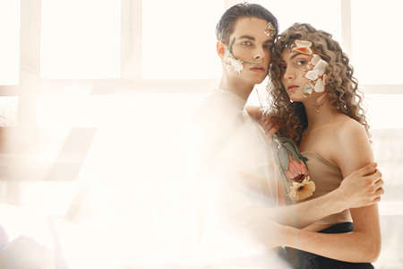 Emotional portrait of a boy and girl with flowers on their faceの写真素材