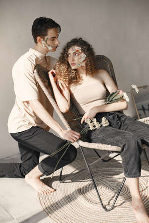 Emotional portrait of a boy and girl with flowers on their faceの写真素材