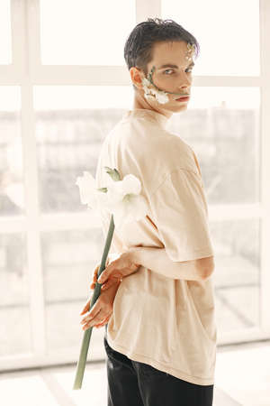 Emotional portrait of a guy with flowers on his faceの写真素材