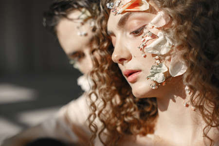 Emotional portrait of a boy and girl with flowers on their faceの写真素材