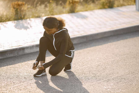 African-american woman in sportswear tying shoelaces at playground outdoorsの写真素材