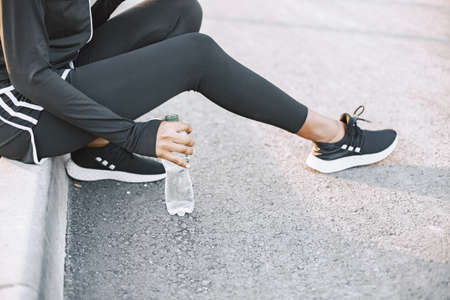 Cropped shot of a woman sitting on a kerb on a streetの写真素材