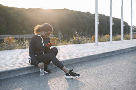 Fit african-american woman looking in a phone while trainingの写真素材