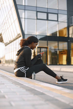 Fit african-american woman looking in a phone while trainingの写真素材
