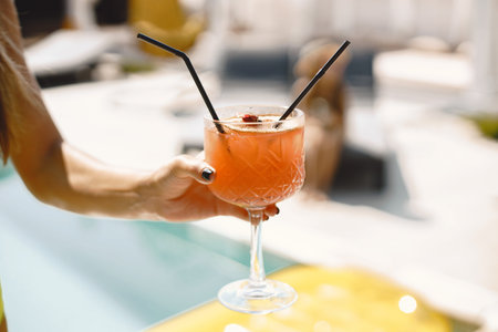 Cocktail in the hands of a woman by pool