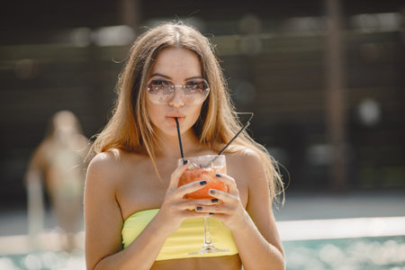 Pretty woman drinking a cocktail at a pool