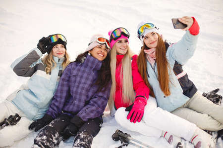 Group of girls taking selfies in mountains on skisの写真素材