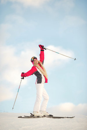 Skier on a mountain slope posing against a background of snow-capped mountainsの写真素材