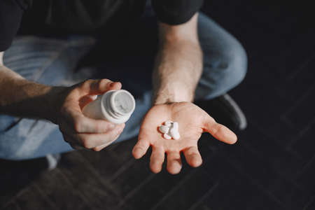 Man with pills sitting on the floorの写真素材