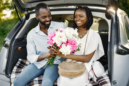 Young happy couple in a park sitting in car trunk